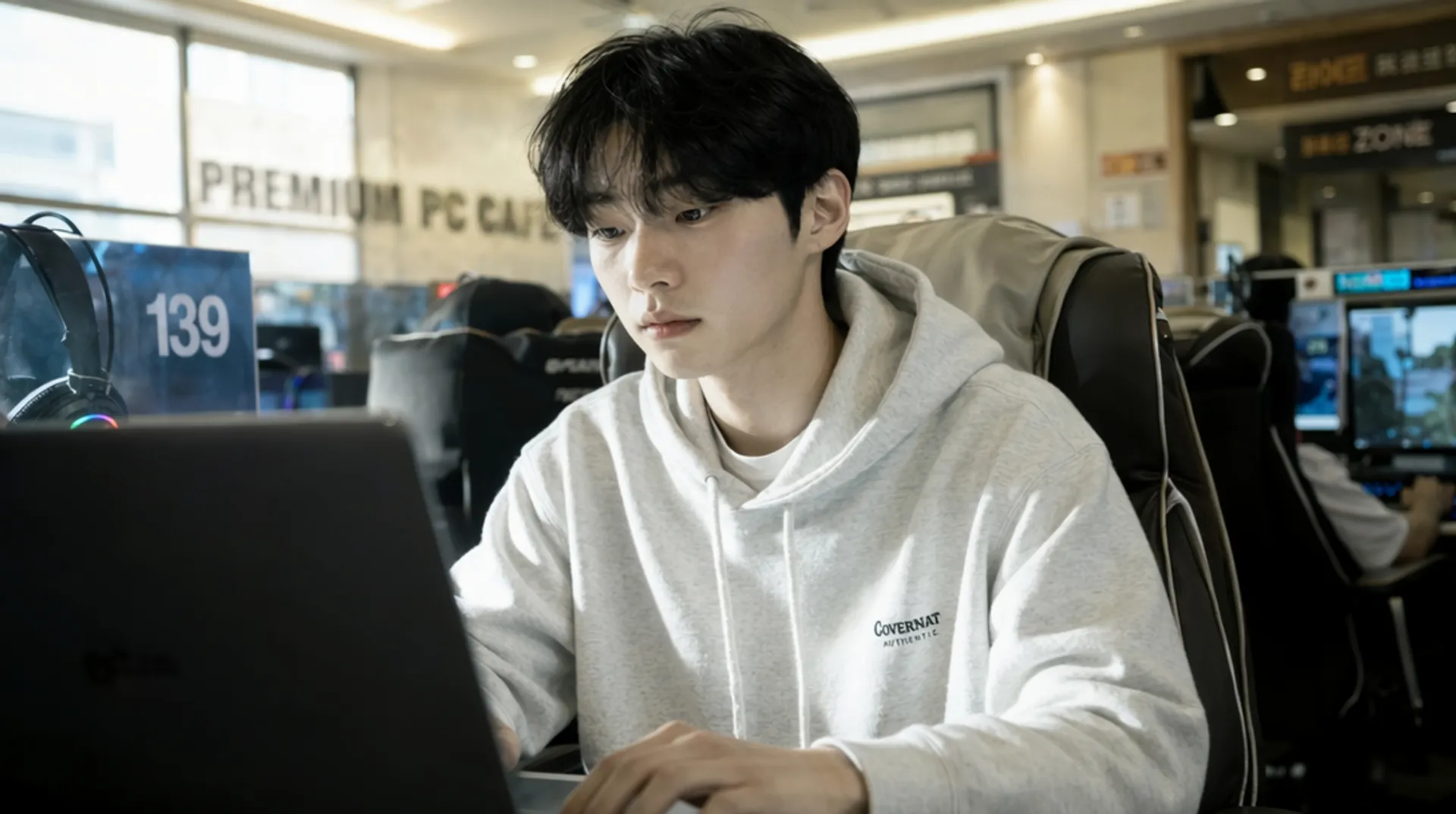 Photorealistic AI-generated candid shot of a young man working on a laptop in a PC cafe