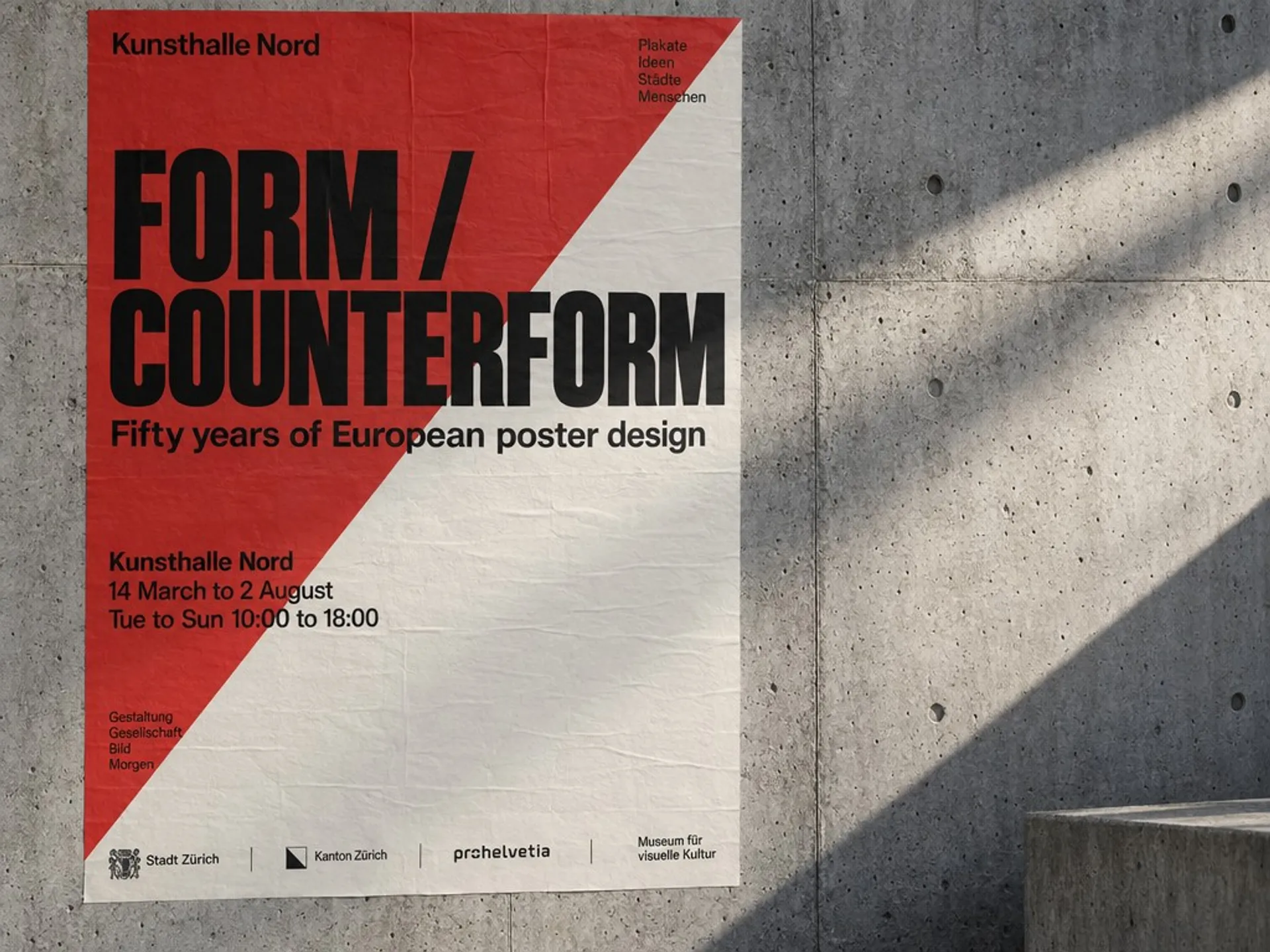 AI-generated Swiss-style exhibition poster pasted to a concrete wall, with a large grotesk headline and a legible venue block