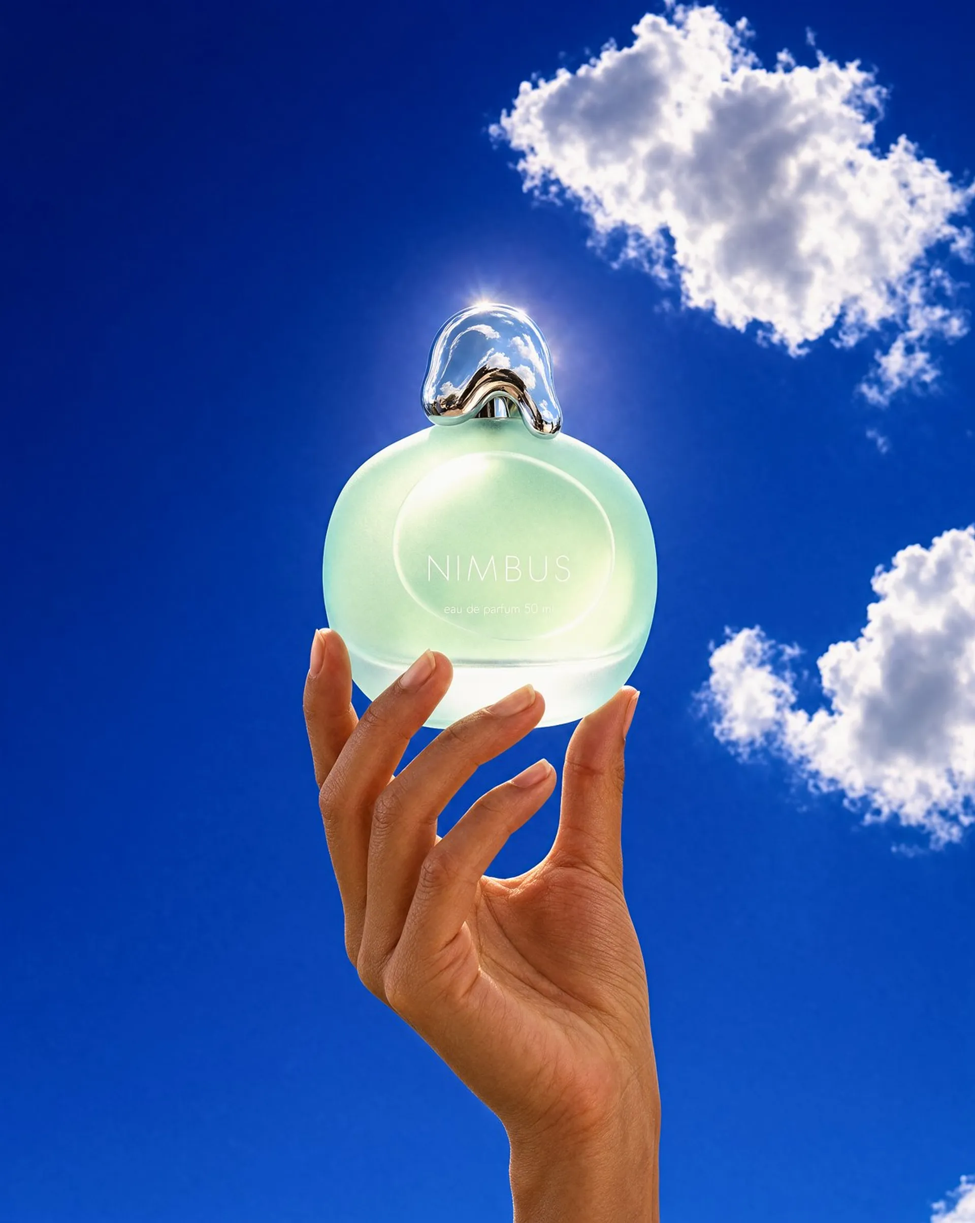 Krea 3 image of a hand raising a frosted seafoam perfume bottle against a cobalt sky with white clouds